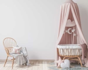 Ein rosa Rattanbabybett mit Himmel und Rattanstuhl (depositphotos.com)