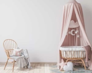 Ein rosa Rattanbabybett mit Himmel und Rattanstuhl (depositphotos.com)