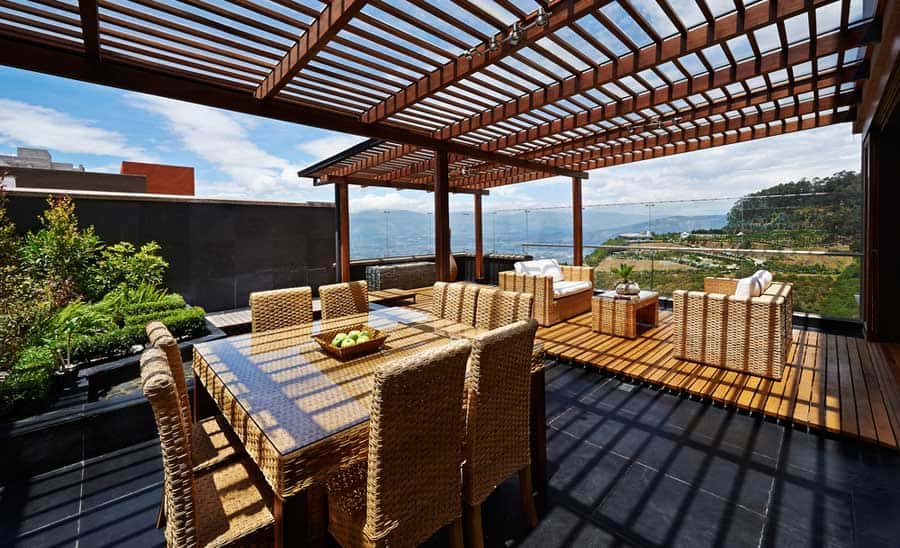 Eine große Terrasse mit Essbereich Eßtisch und Hochlehne Eßstühle und Loungebereich (depositphotos.com)